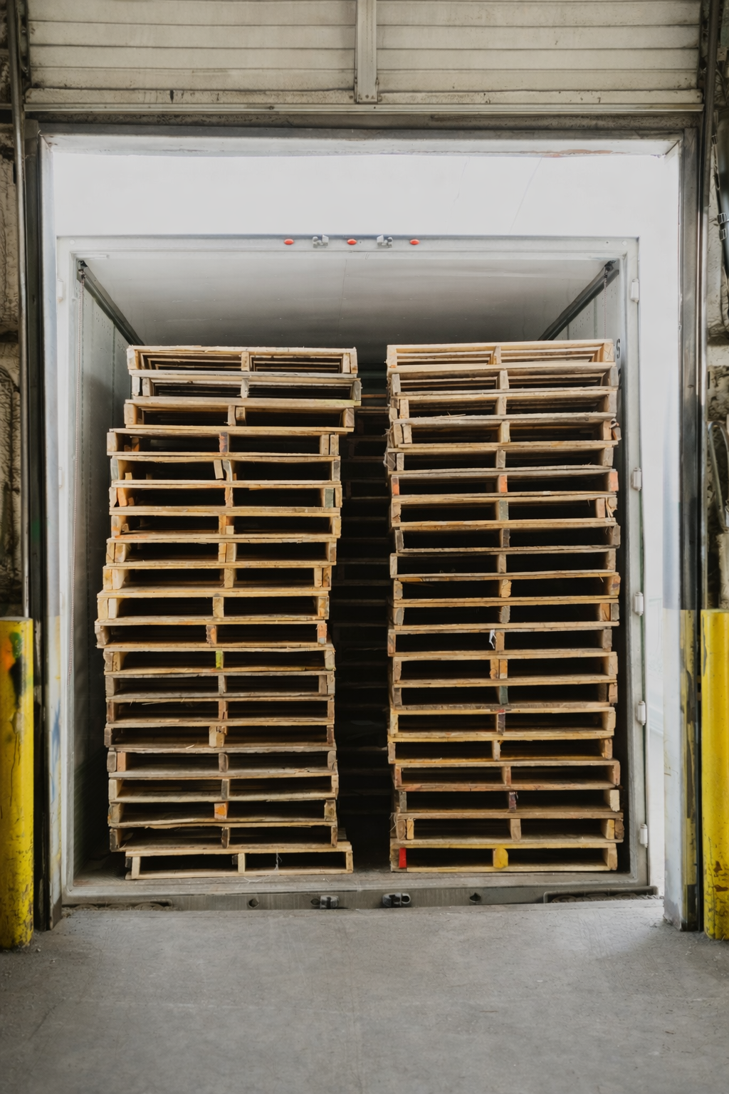 Trailer loaded with stacks of wooden pallets at a loading dock